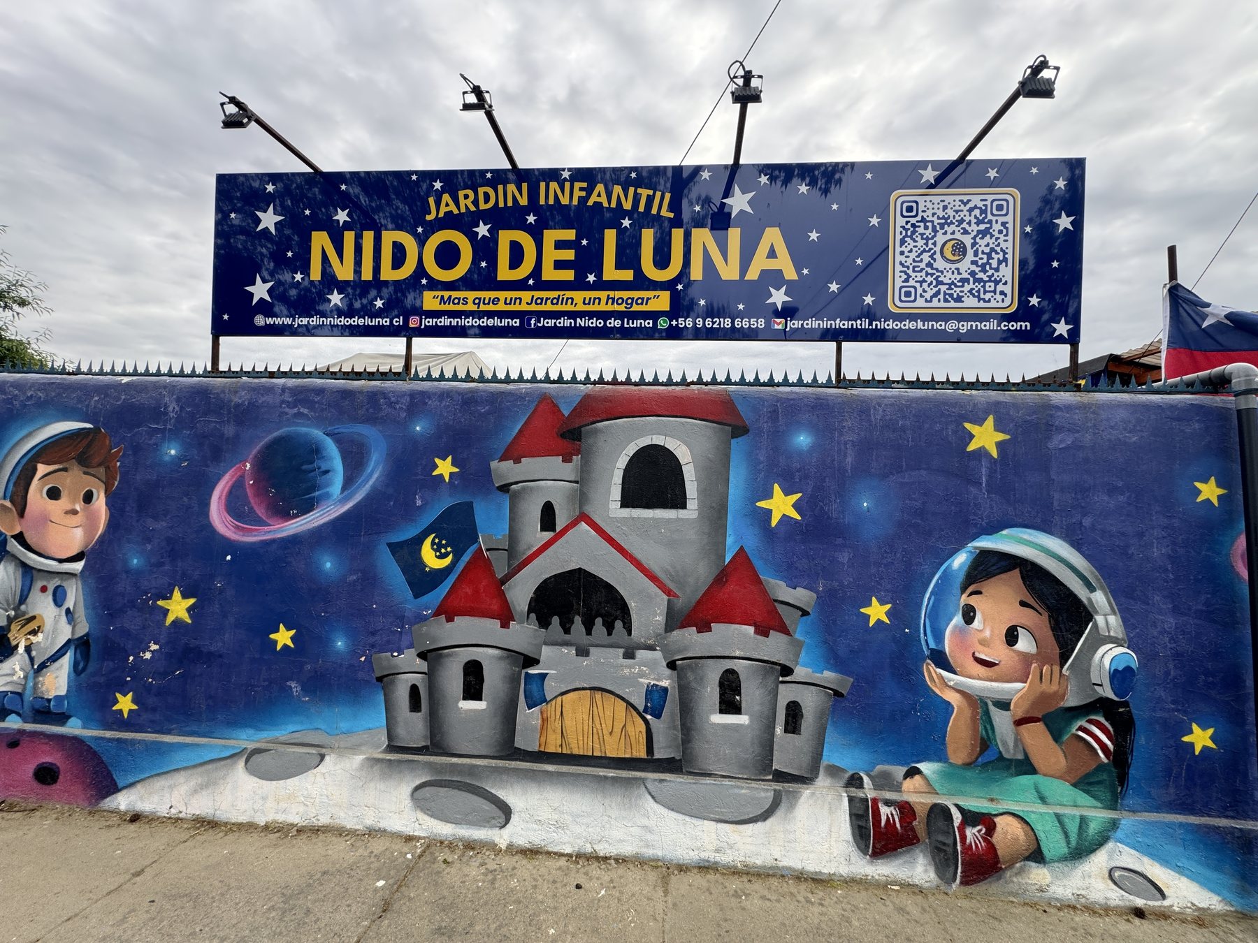 Mural del frontis con un castillo en la luna, niños astronautas y el letrero del jardín