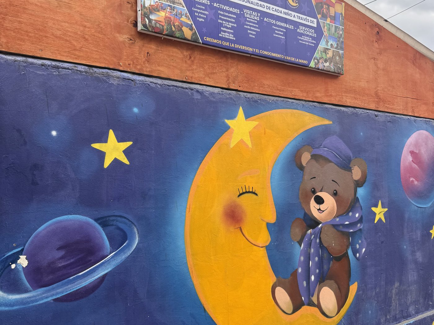 Mural de la luna con un osito en pijama, entre estrellas y planetas