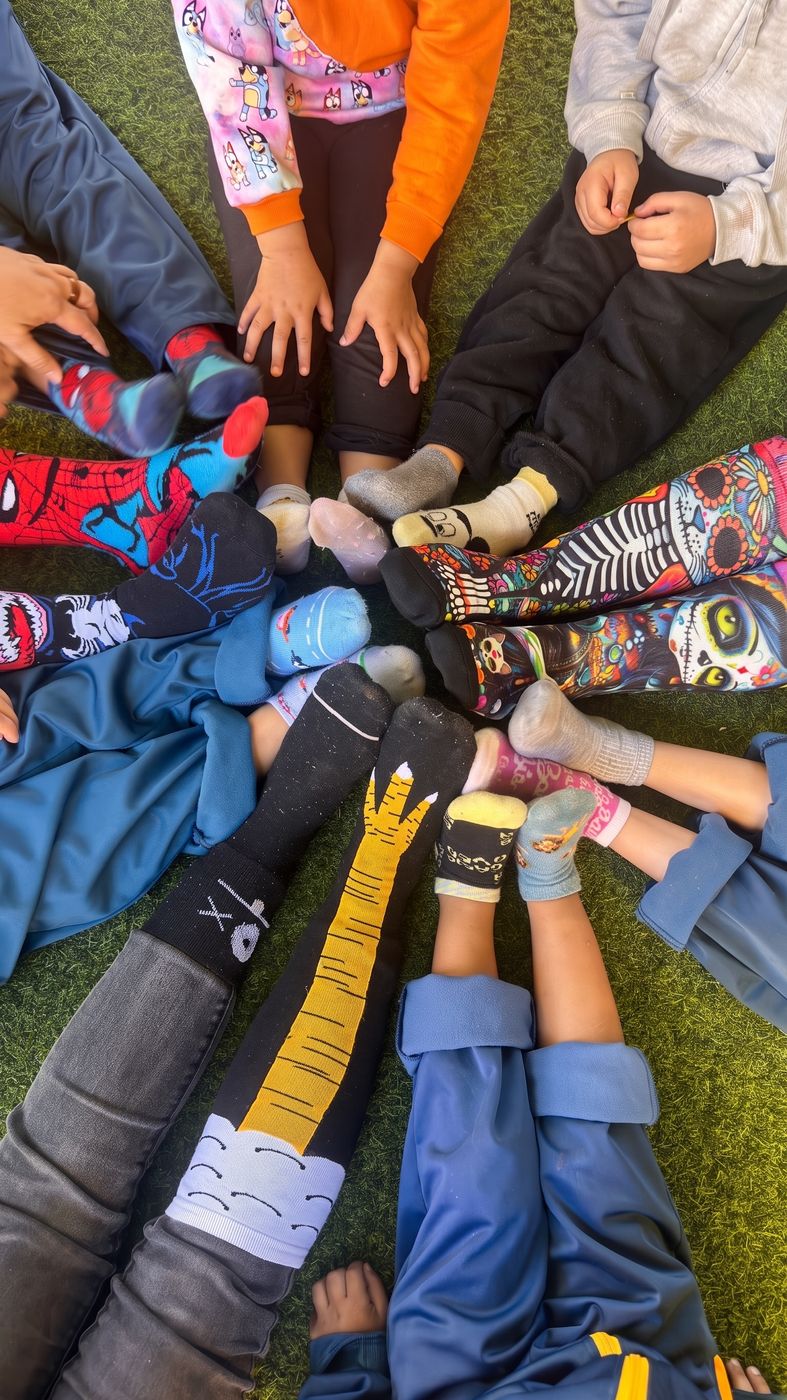 Pies de niños sentados en ronda sobre el pasto, con calcetines de colores