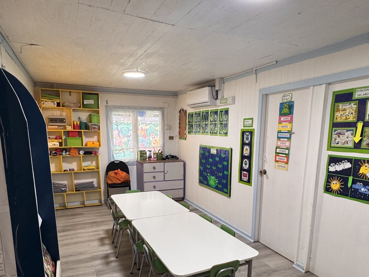 Sala amplia con mesas largas de trabajo y piso de madera