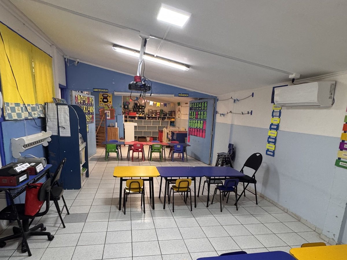 Sala con mesas azules y amarillas y pizarra